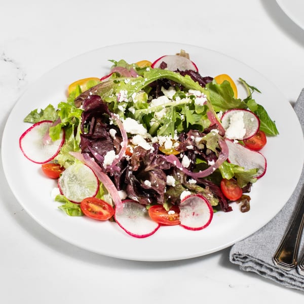Fresh garden salad with mixed greens, radishes, cherry tomatoes, red onion, and feta cheese.